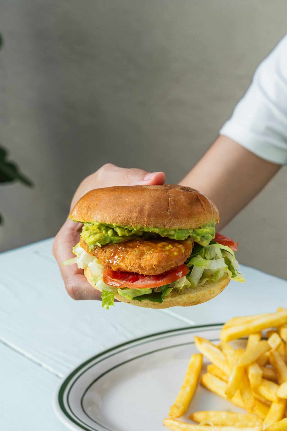 The Pollo Crispy Sandwich with avocado, lettuce and tomato held in two hands